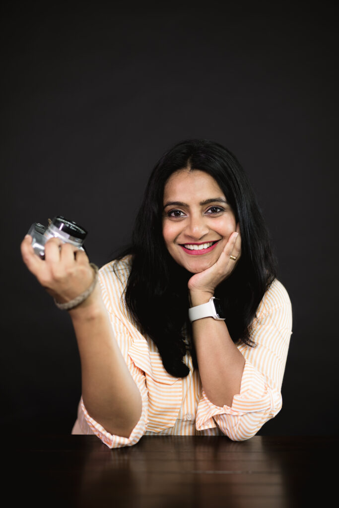 A woman in an orange shirt holding a camera